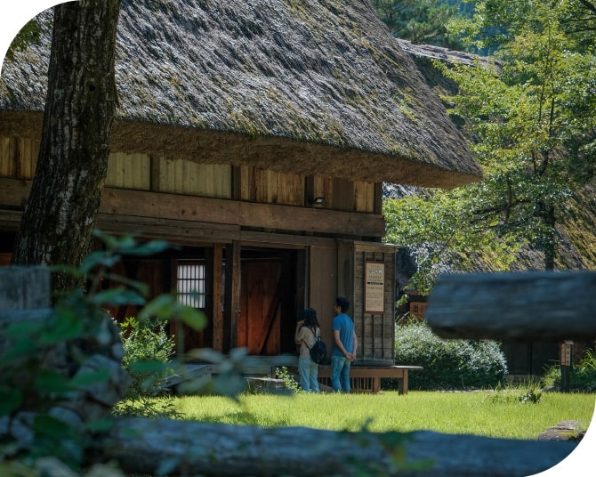 茅葺き屋根の歴史ある建物を見学する観光客